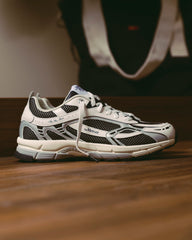 Witte en zilveren sneaker met zwarte meshpanelen, grijze zool en veters