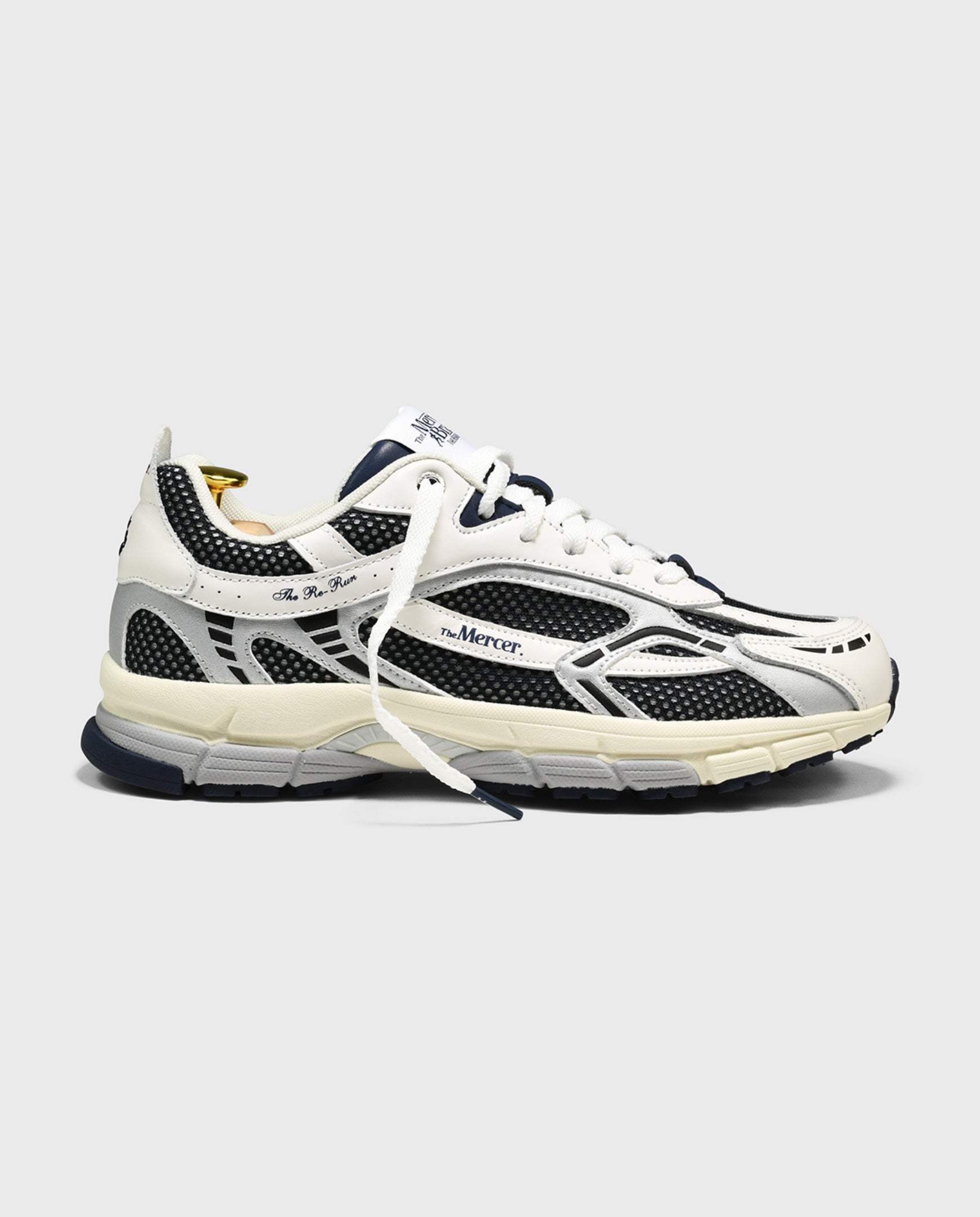 Witte sneaker met blauw-zwarte overlays, veters en sportieve tussenzool