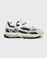 Witte sneaker met blauw-zwarte overlays, veters en sportieve tussenzool