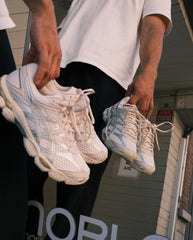 ASICS hardloopschoenen in crème met zilverkleurige accenten, paar in hand gedragen