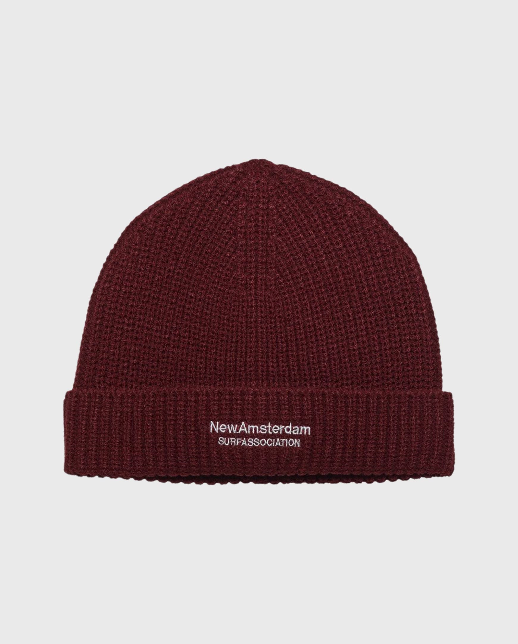 Reversibele beanie donkerrood met NewAmsterdam-logo op geribde boord.