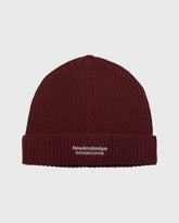 Reversibele beanie donkerrood met NewAmsterdam-logo op geribde boord.
