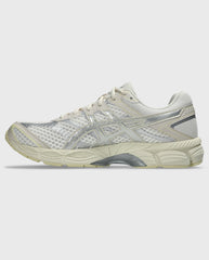 Asics hardloopschoen met crème mesh, zilveren overlays en geprofileerde zool.