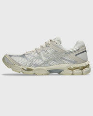 Asics hardloopschoen met crème bovenwerk, zilveren accenten en dempende tussenzool.