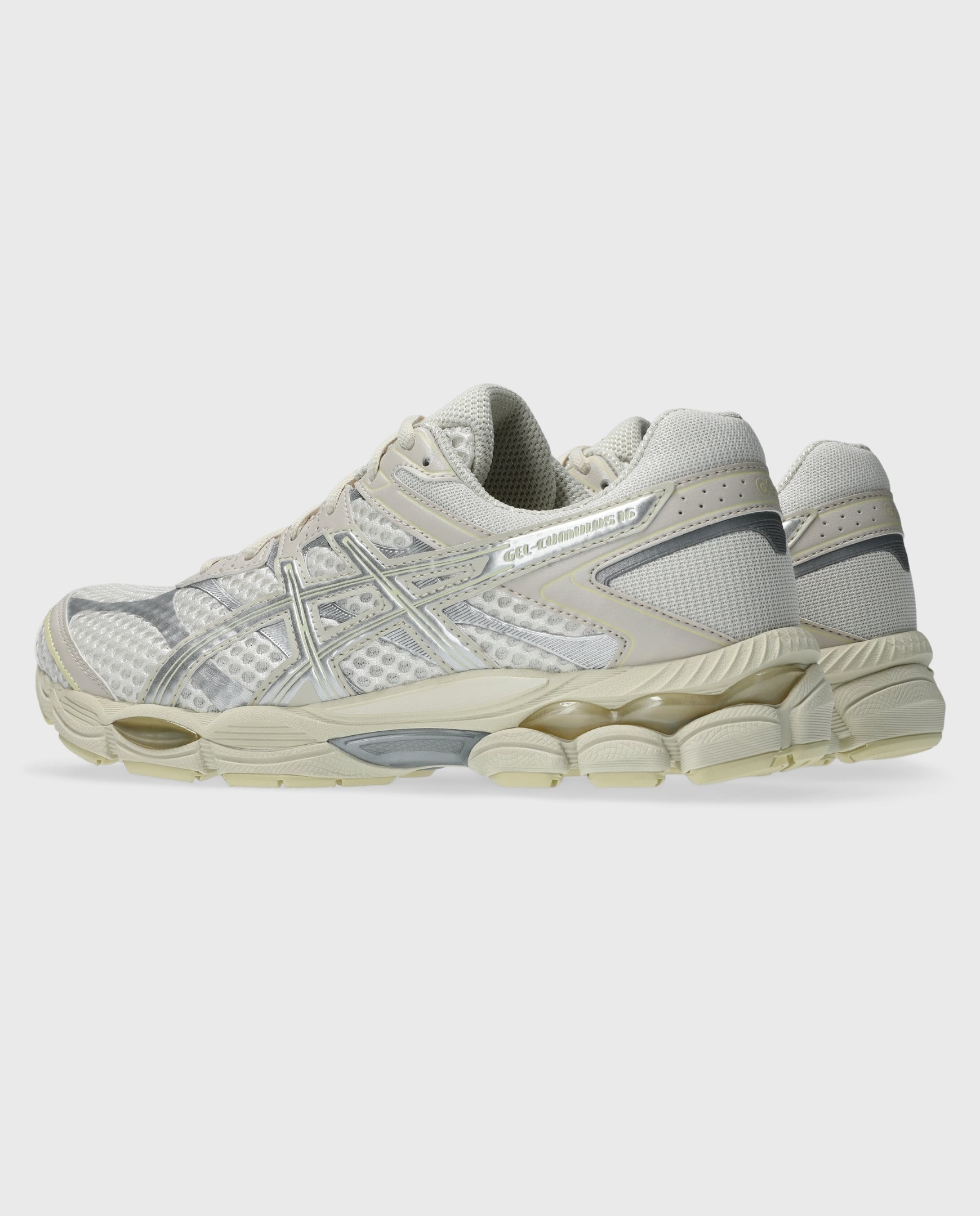 Asics hardloopschoen met crème bovenwerk, zilveren stripes en lichtgekleurde zool.