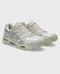 Asics hardloopschoen met crème veters, zilveren mesh-bovenwerk en dempende zool.