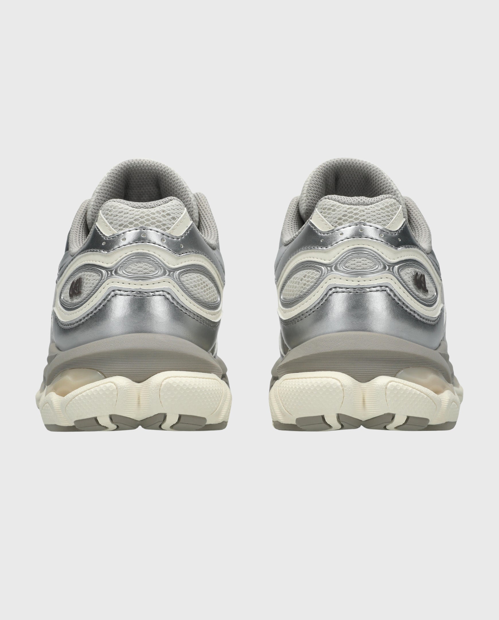 Sneaker achteraanzicht met zilveren hielrand en beige tussenzool, vetersluiting.