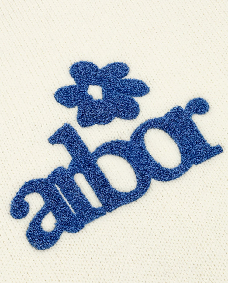 Beige alpaca gebreide trui met blauw 'albor' logo en bloem op de borst