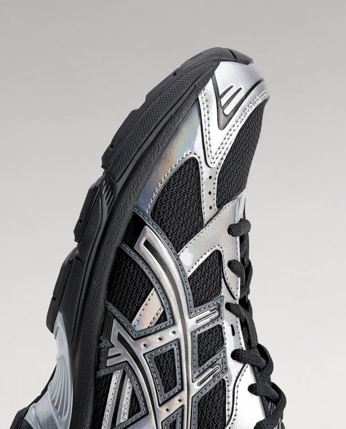 Asics sneakers, detail van zijkant met geperforeerde panelen in zwart, wit en zilver