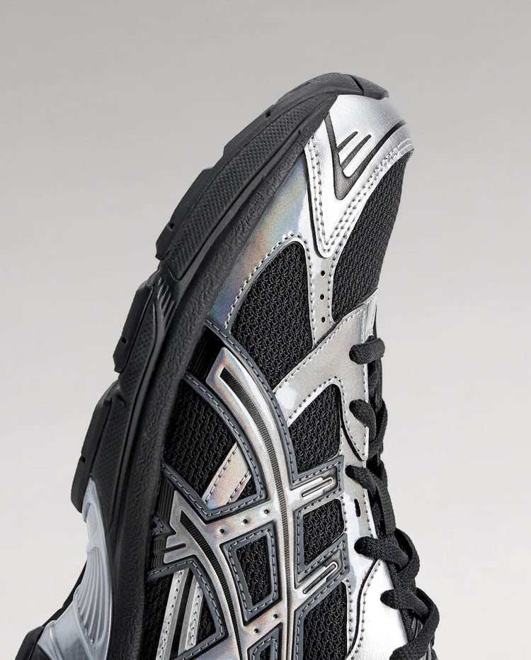 Asics sneakers, detail van zijkant met geperforeerde panelen in zwart, wit en zilver