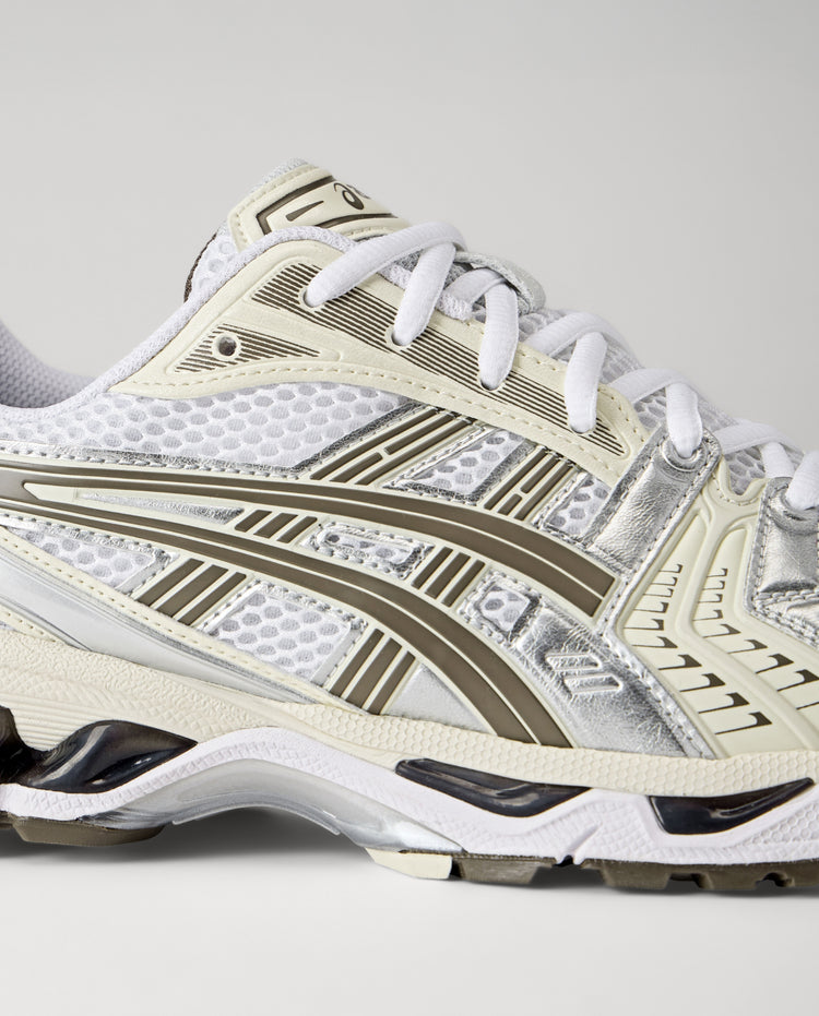 Zijkant witte ASICS Gel-Kayano 14 sneaker met streeppanelen en mesh patroon