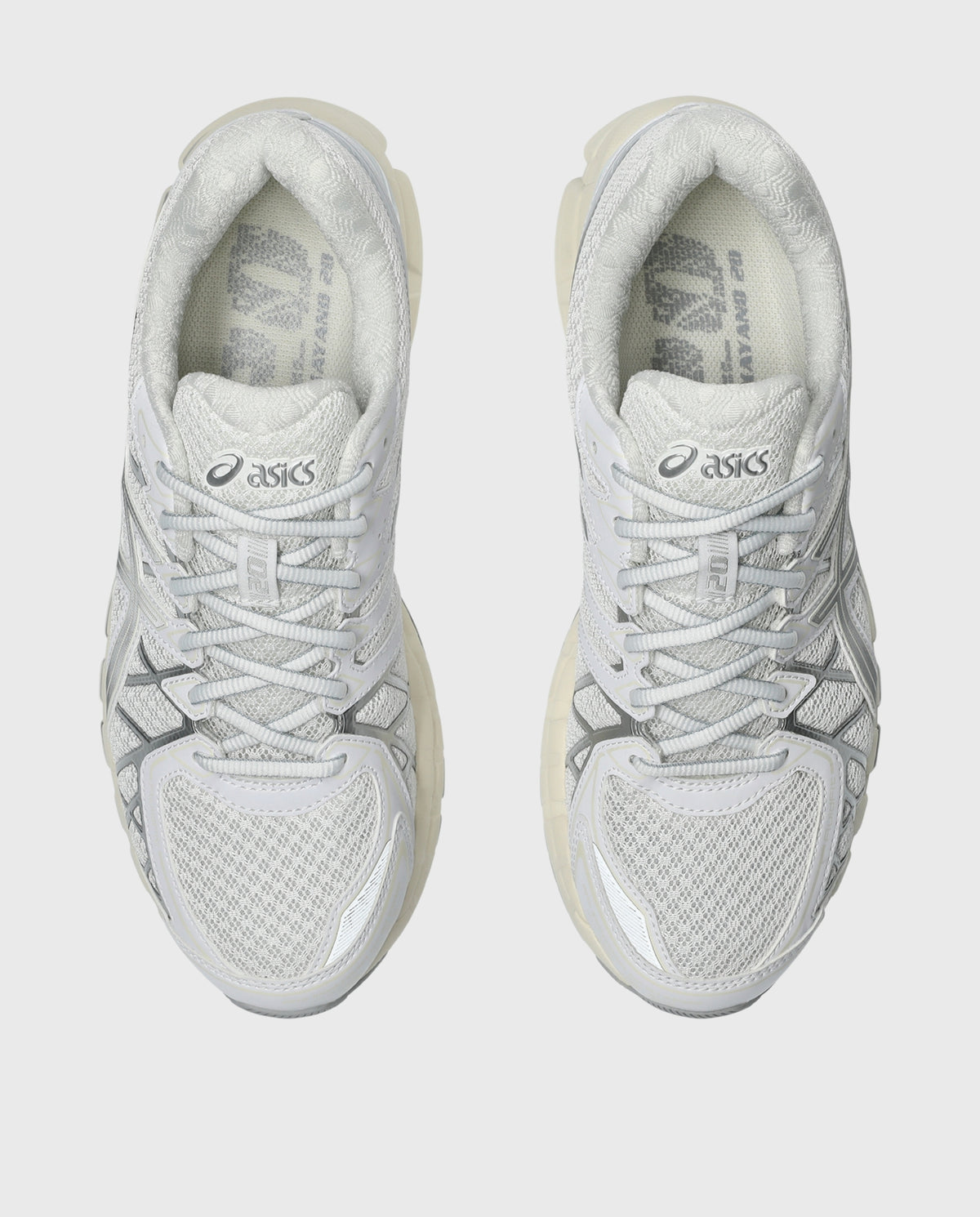 Witte Asics hardloopschoenen, zijaanzicht met zilveren details en vetersluiting.