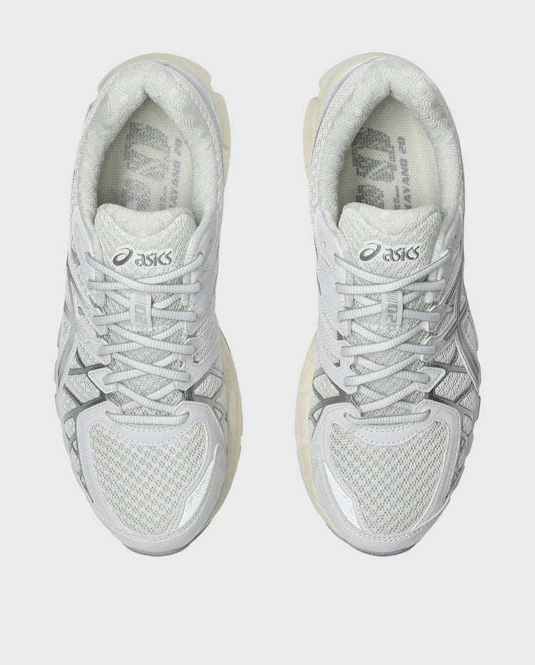 Witte Asics hardloopschoenen, zijaanzicht met zilveren details en vetersluiting.
