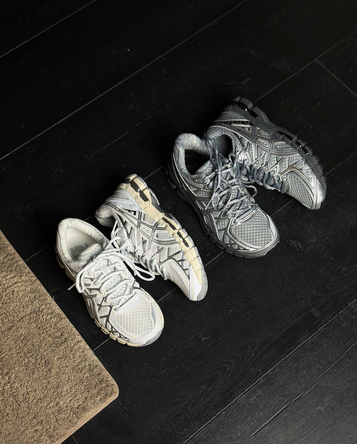 Paar witte Asics hardloopschoenen opzij, zilveren overlays en crème tussenzool zichtbaar.