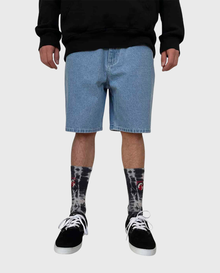 Lichtblauwe denim shorts tot op de knie, met zwarte sokken en sneakers