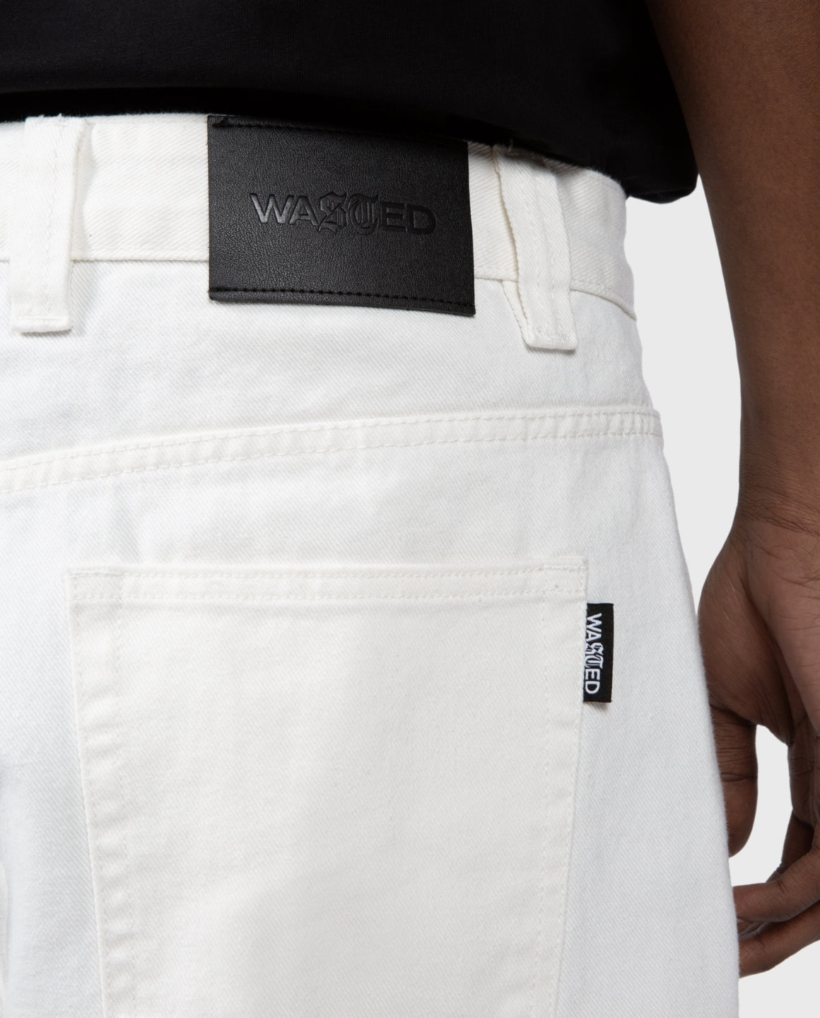 Casper broek off-white close-up: zwarte merketiket op achterzak en stiksels