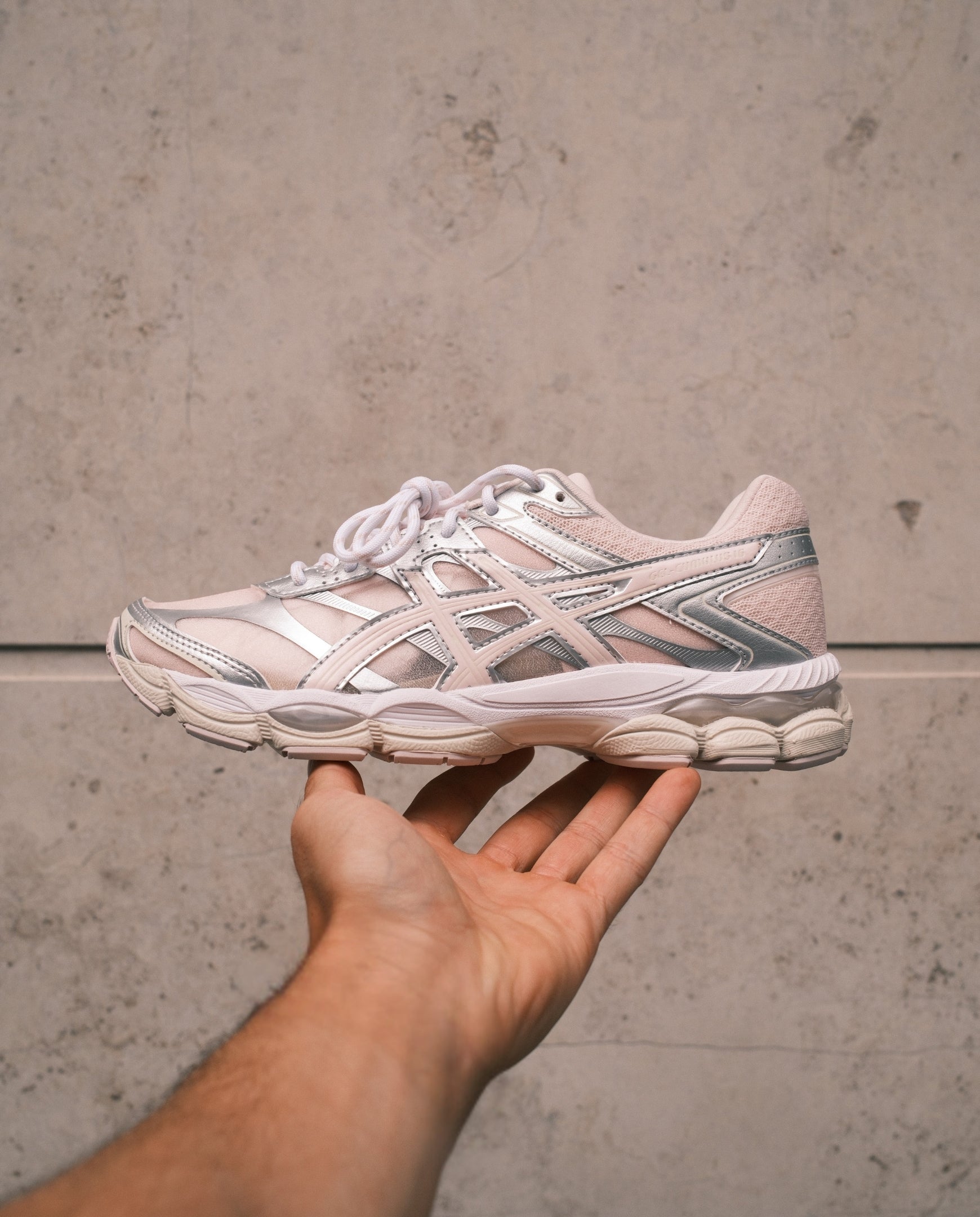 Roze Asics hardloopschoen met zilveren accenten en veters, zijkant zichtbaar
