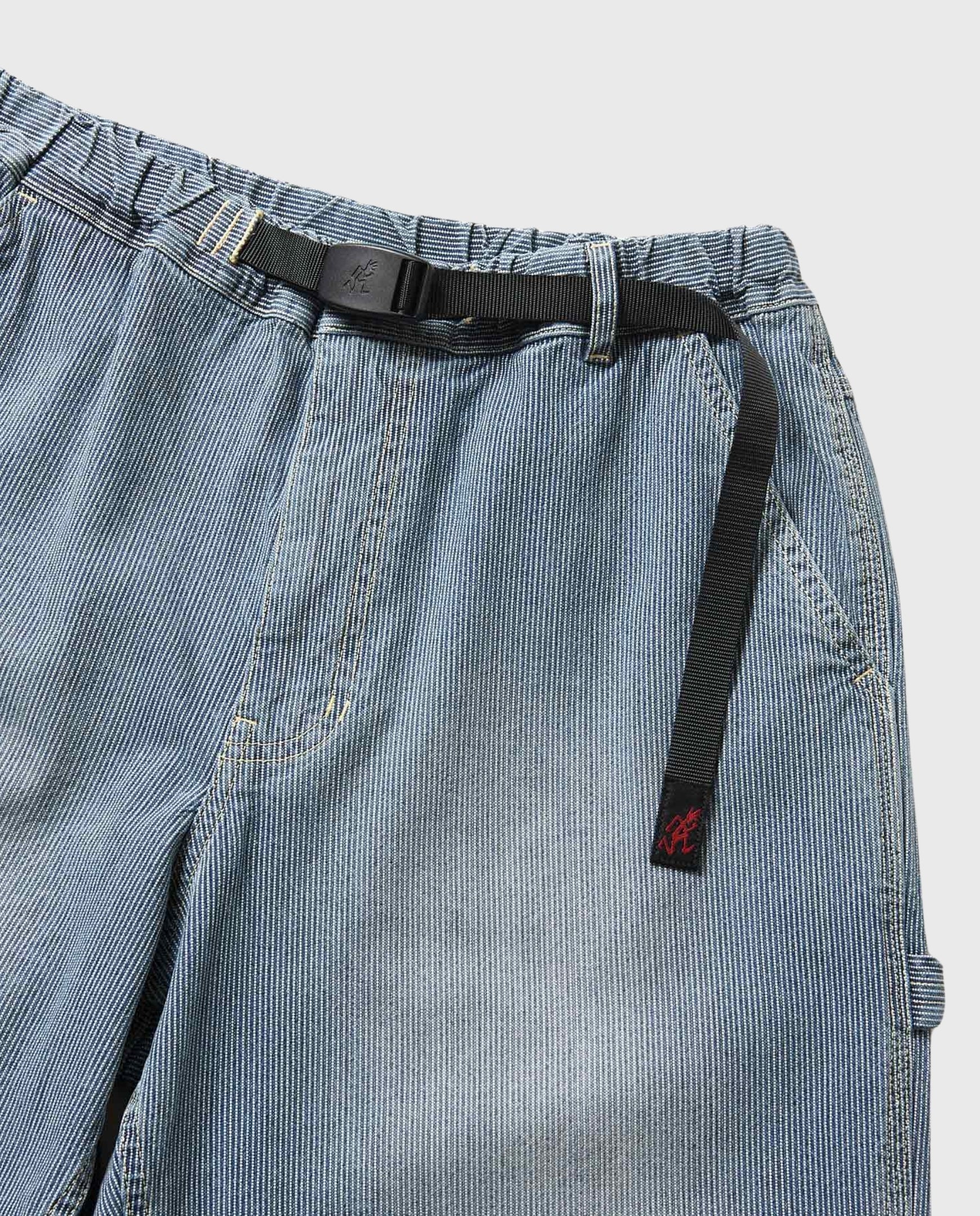 Detail van elastische tailleband met zwarte riem en trekkoord in lichtblauwe denim