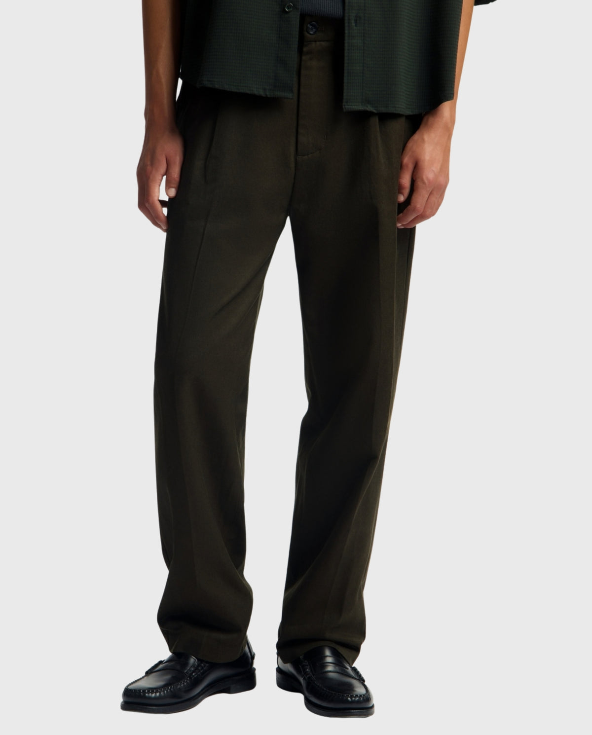 Donkergroene pantalon met rechte pijpen, knoopsluiting en zijzakken.