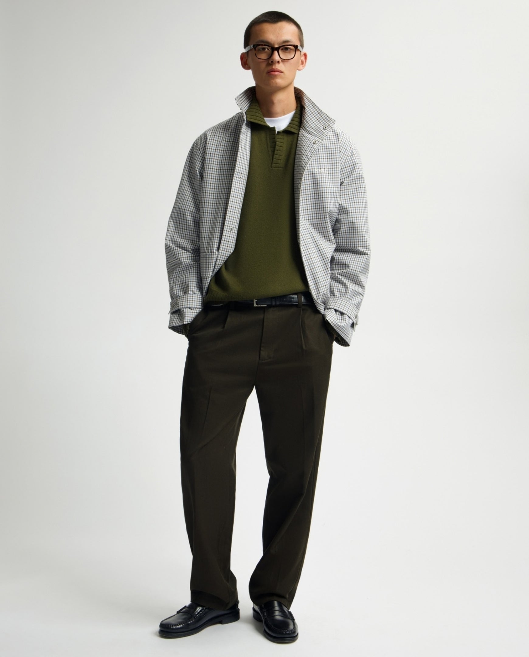Donkergroene pantalon met rechte pijpen, riemlussen en knoopsluiting; volledige broek.