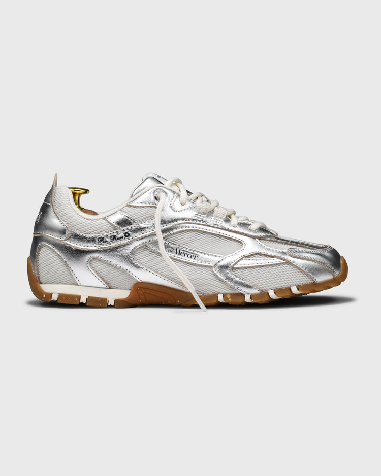 Zilveren sneaker zijaanzicht met witte veters en bruine rubberen zool