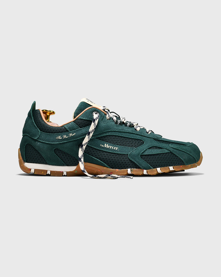 Groene sneaker met veters, bruine zool en goudkleurige accenten, zijaanzicht