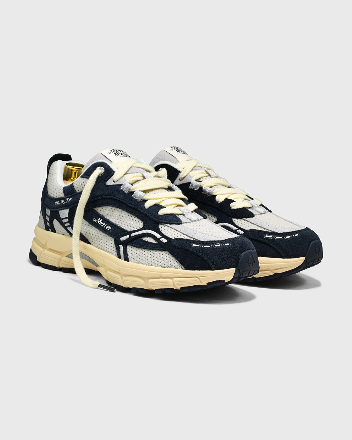 Donkerblauwe sneakers met witte mesh bovenkant en beige tussenzool, driekwartaanzicht