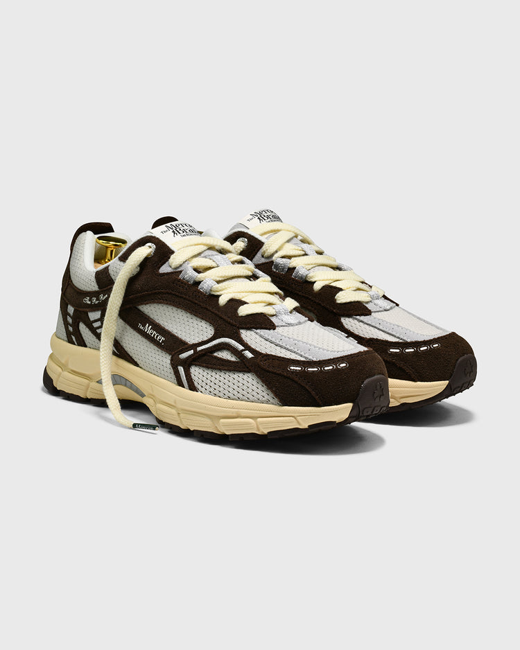 Bruine sneaker met wit mesh en beige zool, 3/4 vooraanzicht.