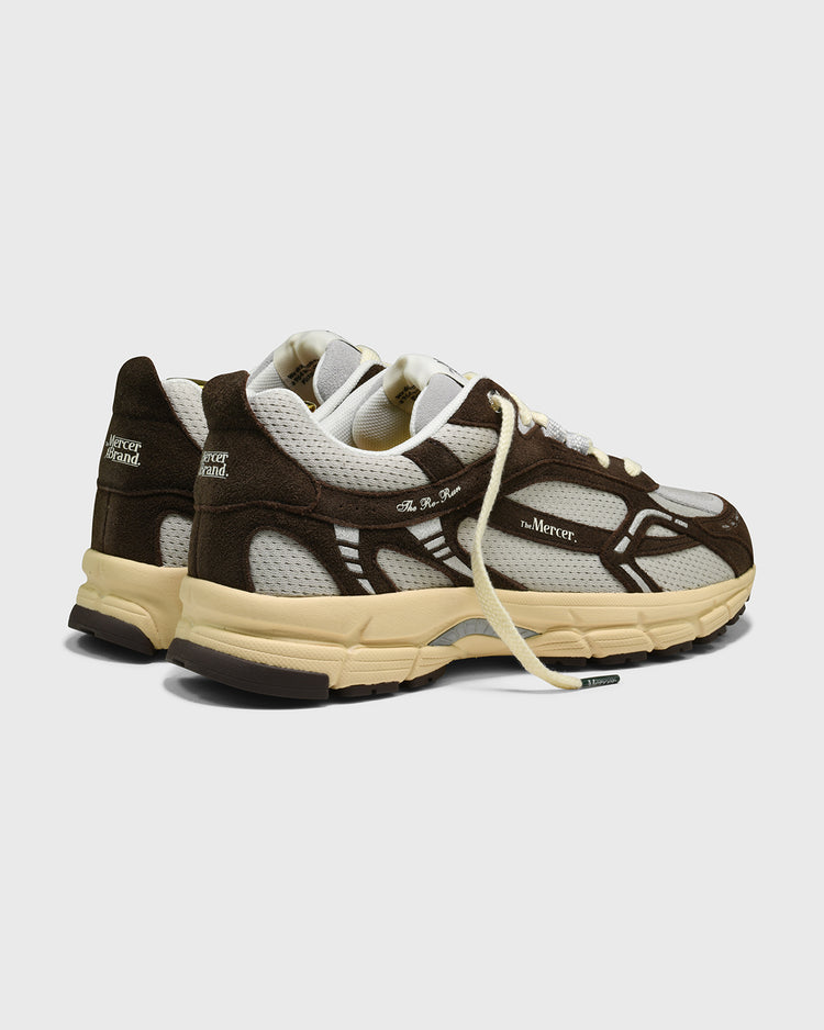 Bruine sneaker met wit bovenwerk, achteraanzicht met crèmekleurige zool.