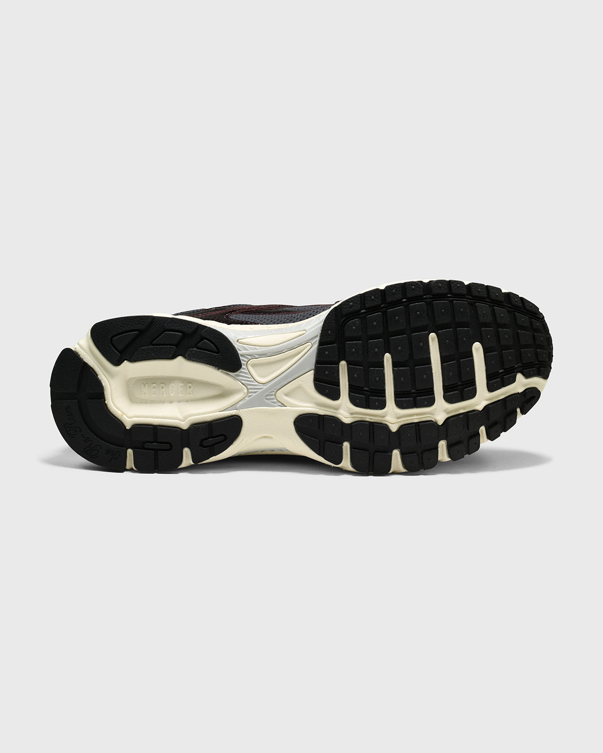 Sneakers zolenaanzicht: donker rubber met crème details en lichte tussenzool
