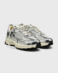 Zilveren sneaker met glanzende gekraakte bovenkant, witte veters en zwarte neus