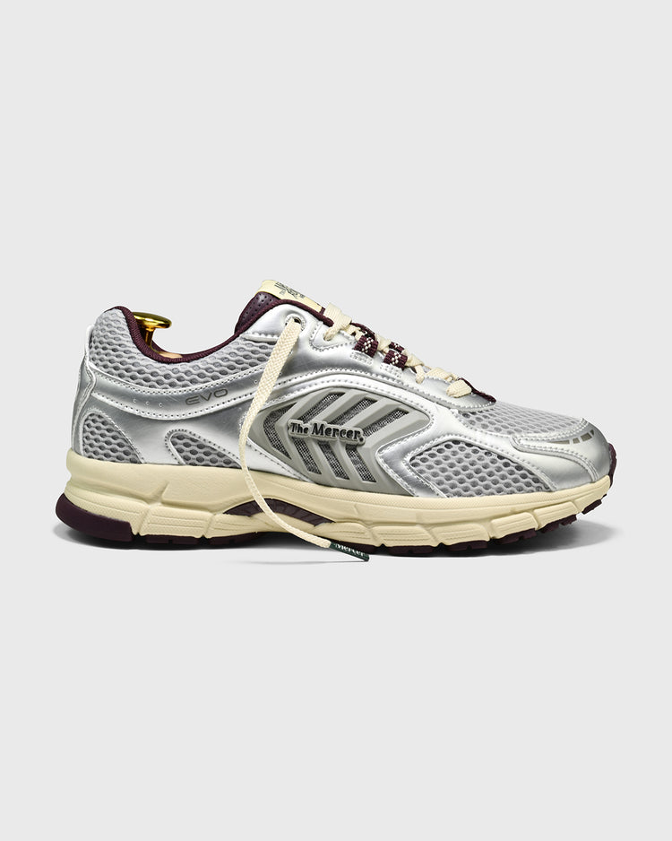 Zilveren sneaker met bordeauxrode accenten en mesh bovenwerk, zijaanzicht.