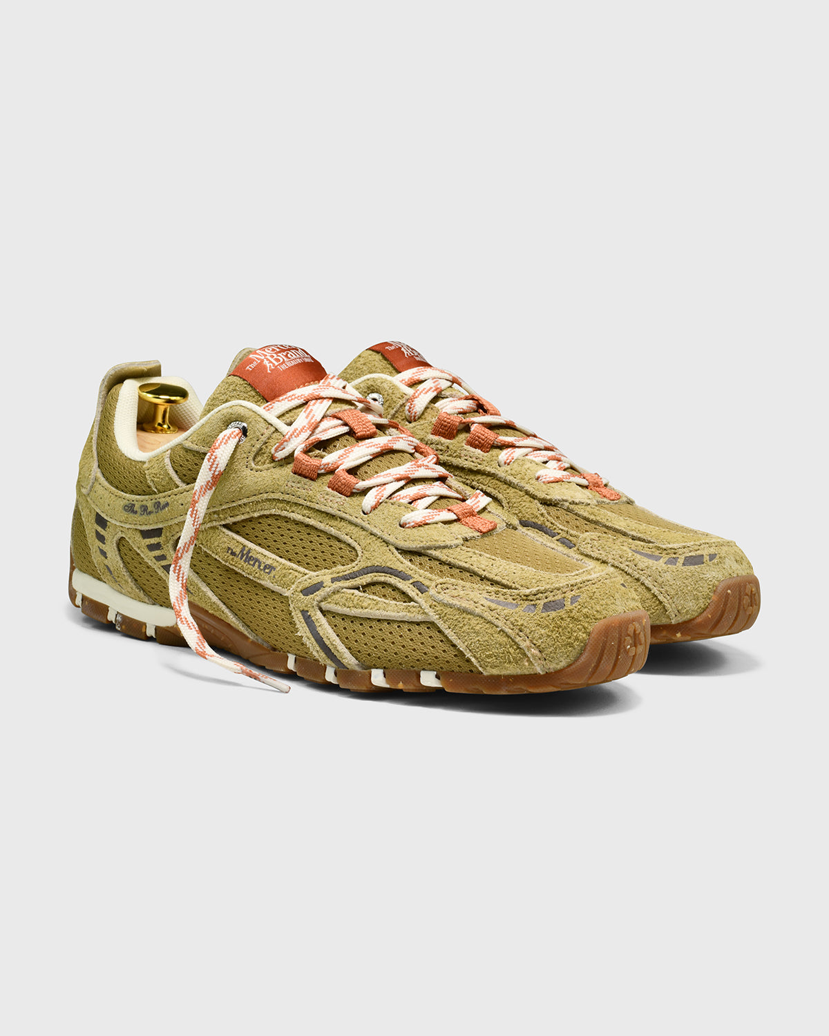 Olijfgroene suède sneaker met veters en oranje details, vooraanzicht schuin.