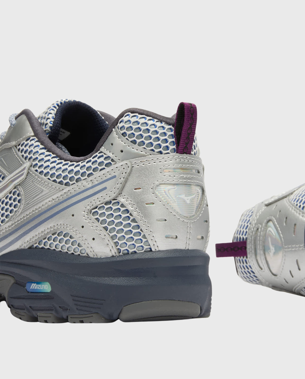 Mizuno hardloopschoen met zilver mesh, grijze overlays en paarse hielband.