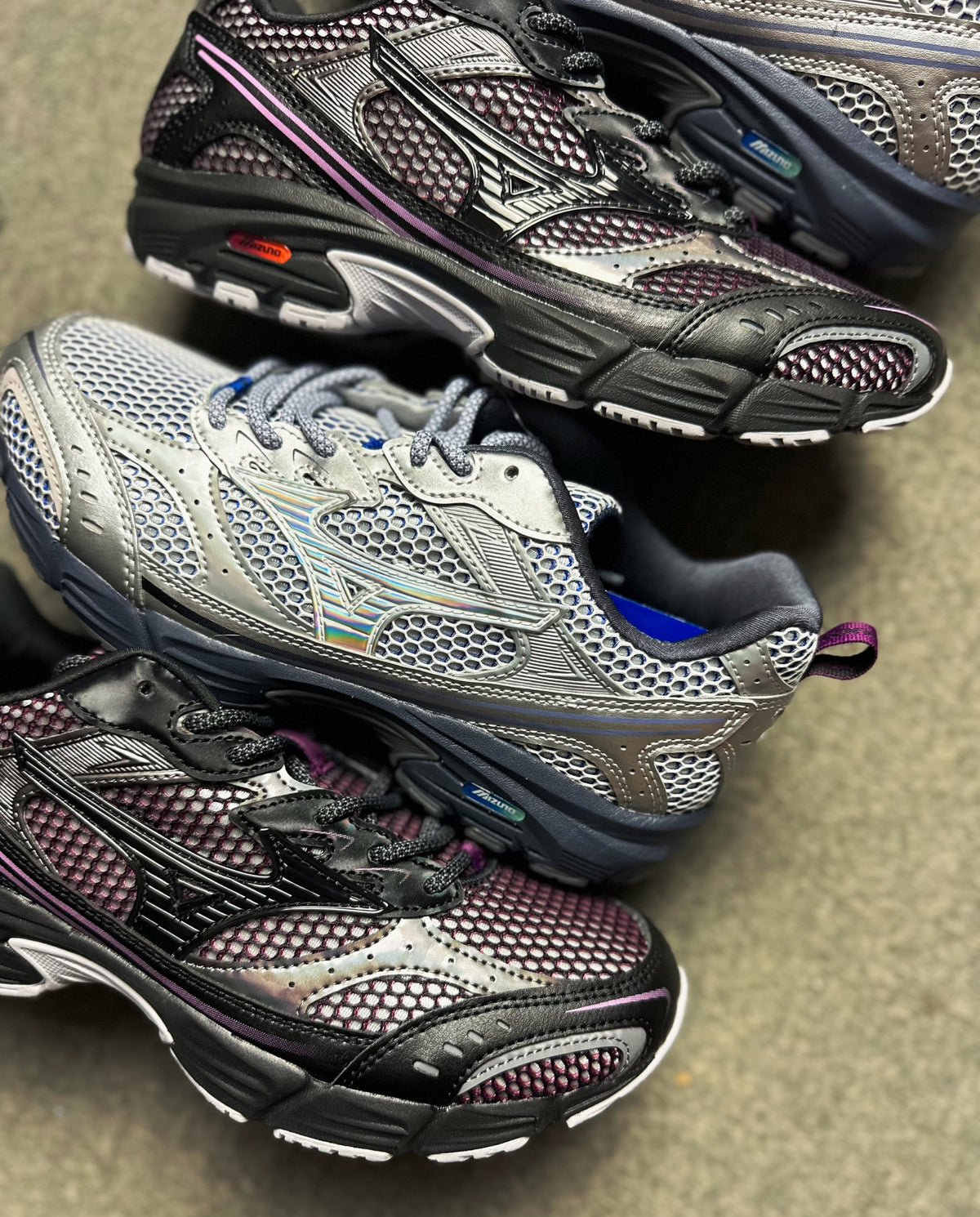 Mizuno hardloopschoenen set: zwarte mesh met paarse bies en blauw-oranje hielaccent.