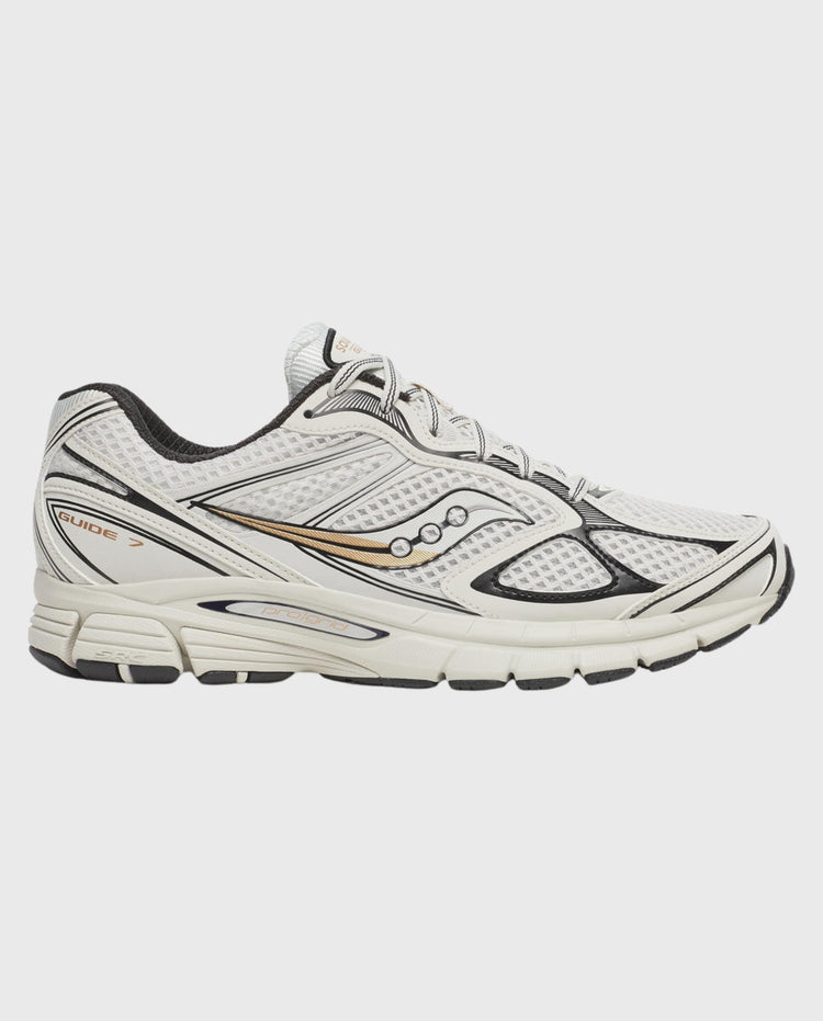 Witte hardloopschoenen met veters, zwarte overlays en oranje Saucony-details