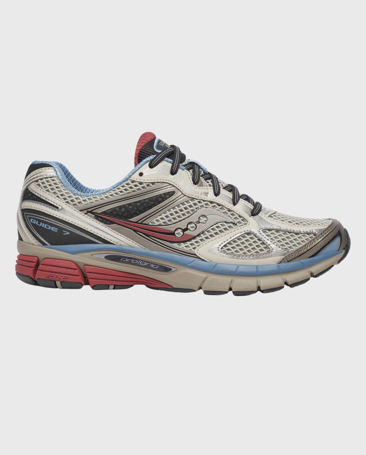 Saucony hardloopschoen in taupe met blauwe veters, zwarte zijkant en rode zool
