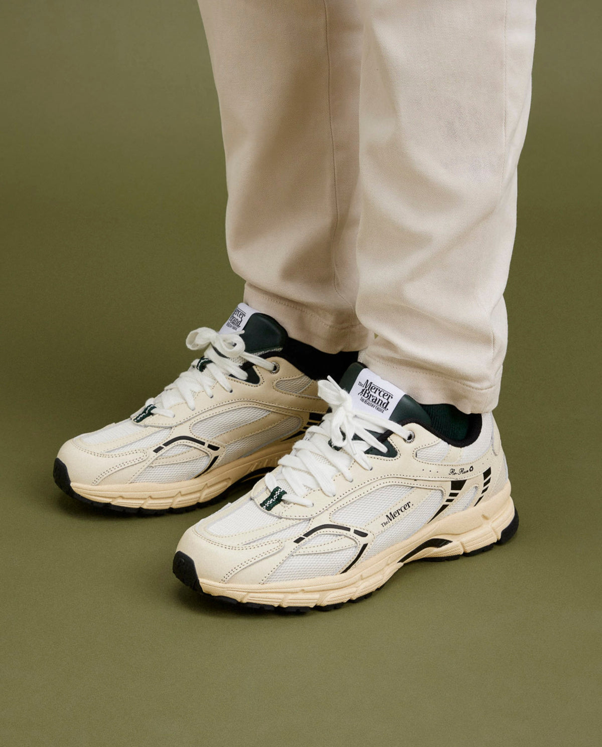 Witte sneakers met groene veters, zwarte hielkraag en dikke zool