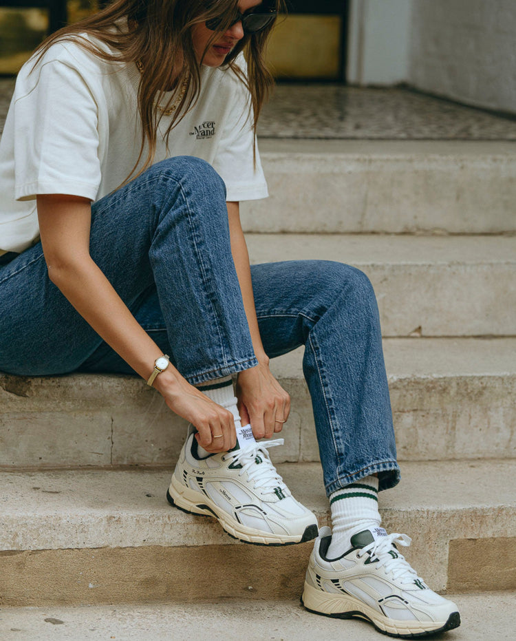 Witte sneakers met groene veters en zwarte hielkraag, zichtbaar profiel van de zool