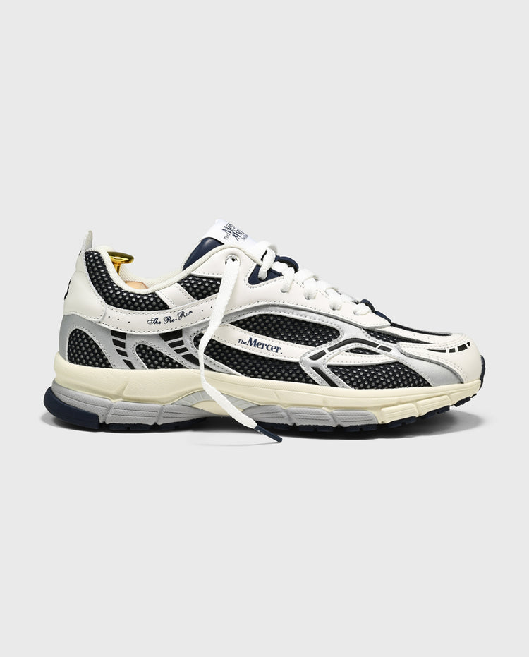 Witte sneaker met blauw-zwarte overlays, veters en sportieve tussenzool