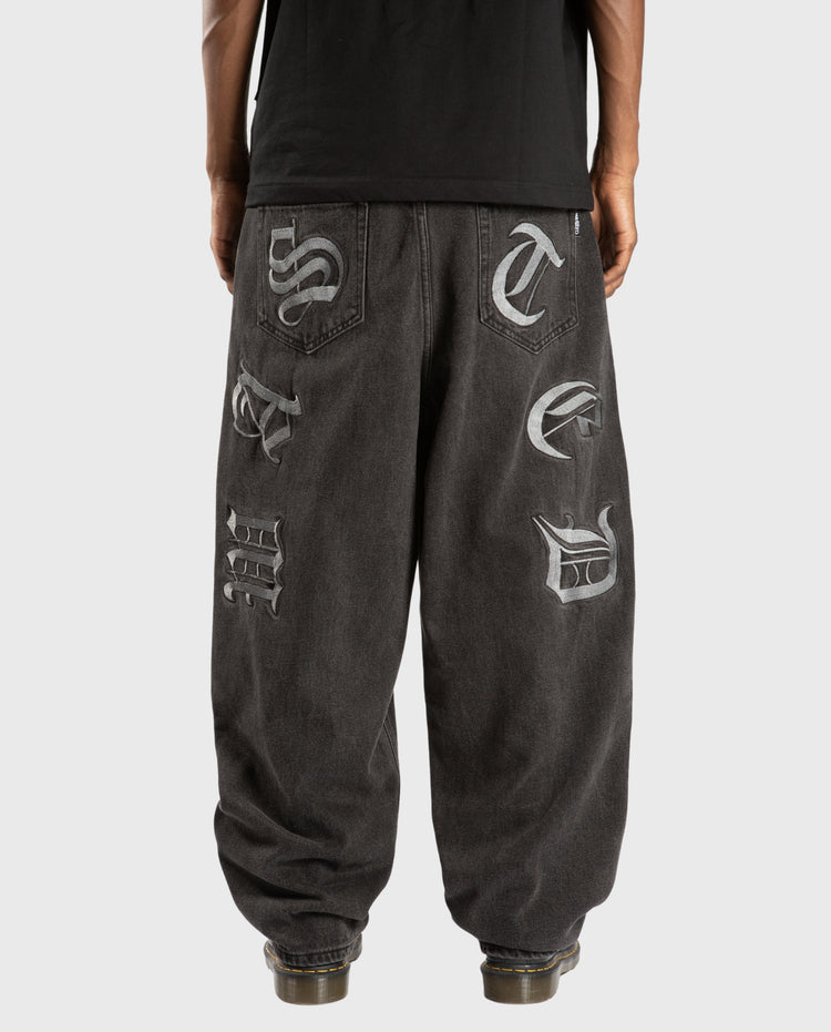 Zwarte faded jeans met grote logo-patches op de pijpen