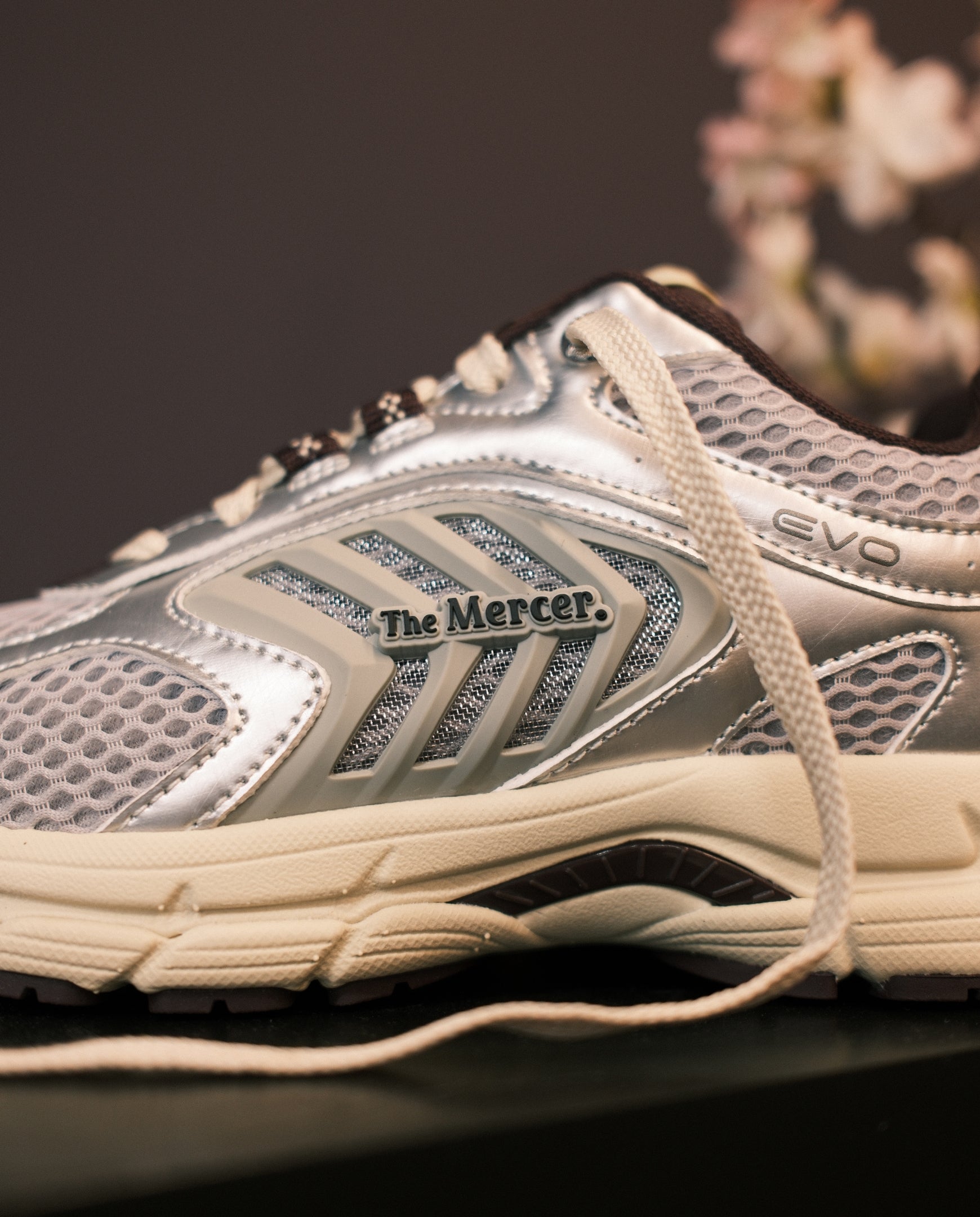Zilveren sportsneaker met The Mercer- en EVO-stiksels, mesh bovenwerk.