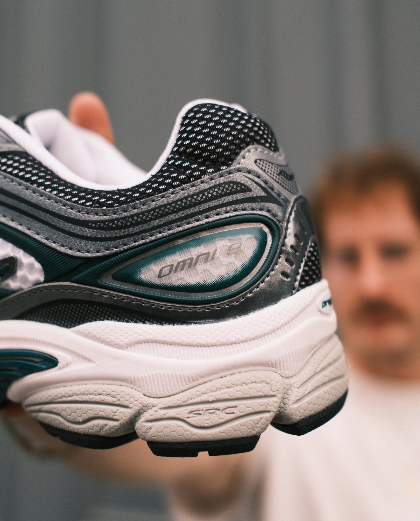 Saucony hardloopschoen met zwarte mesh, groene panelen en witte zool, vetersluiting