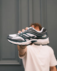 Saucony hardloopschoen met wit-grijze bovenkant, zwarte en groene details en dikke witte zool