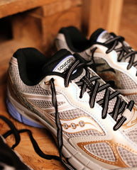 Witte en beige Saucony Progrid sneakers met zwarte veters en oranje inzetstukken