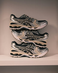 Asics Gel-Kayano 14 hardloopschoenen in grijs en zwart, paar op elkaar gestapeld