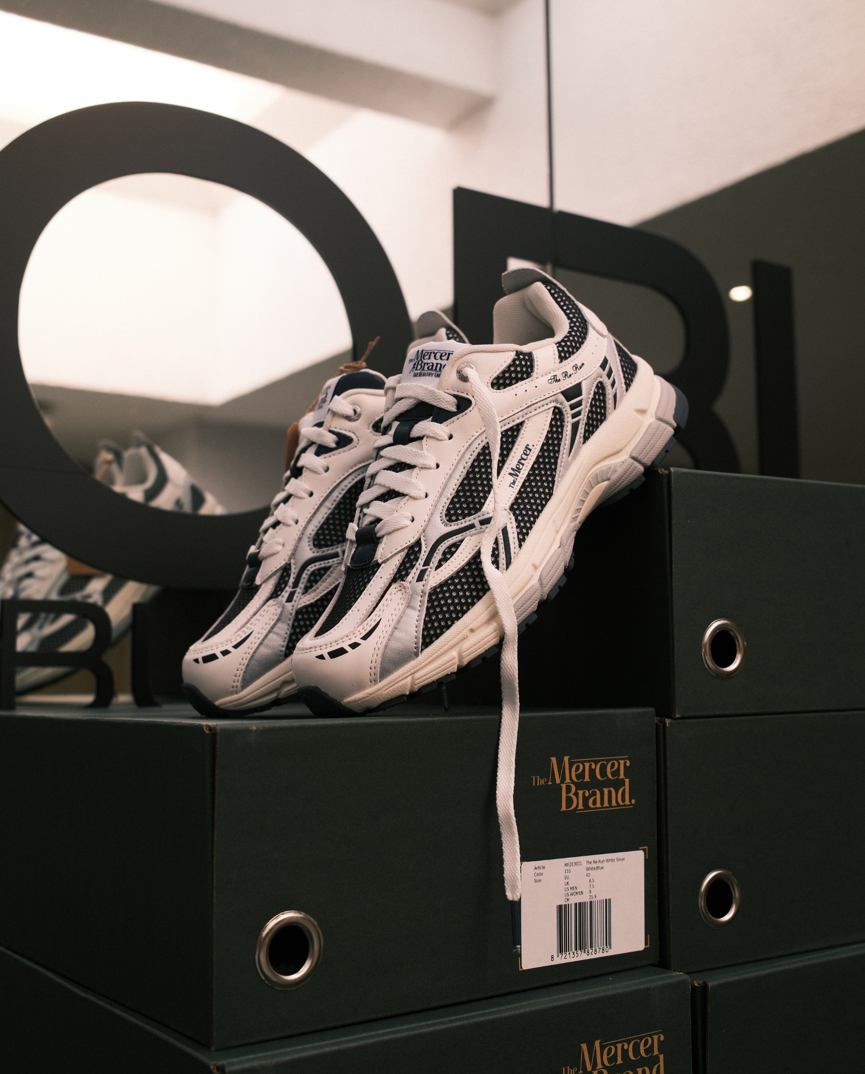 Lichtroze sneaker op zwarte schoenendoos met zwarte meshdetails