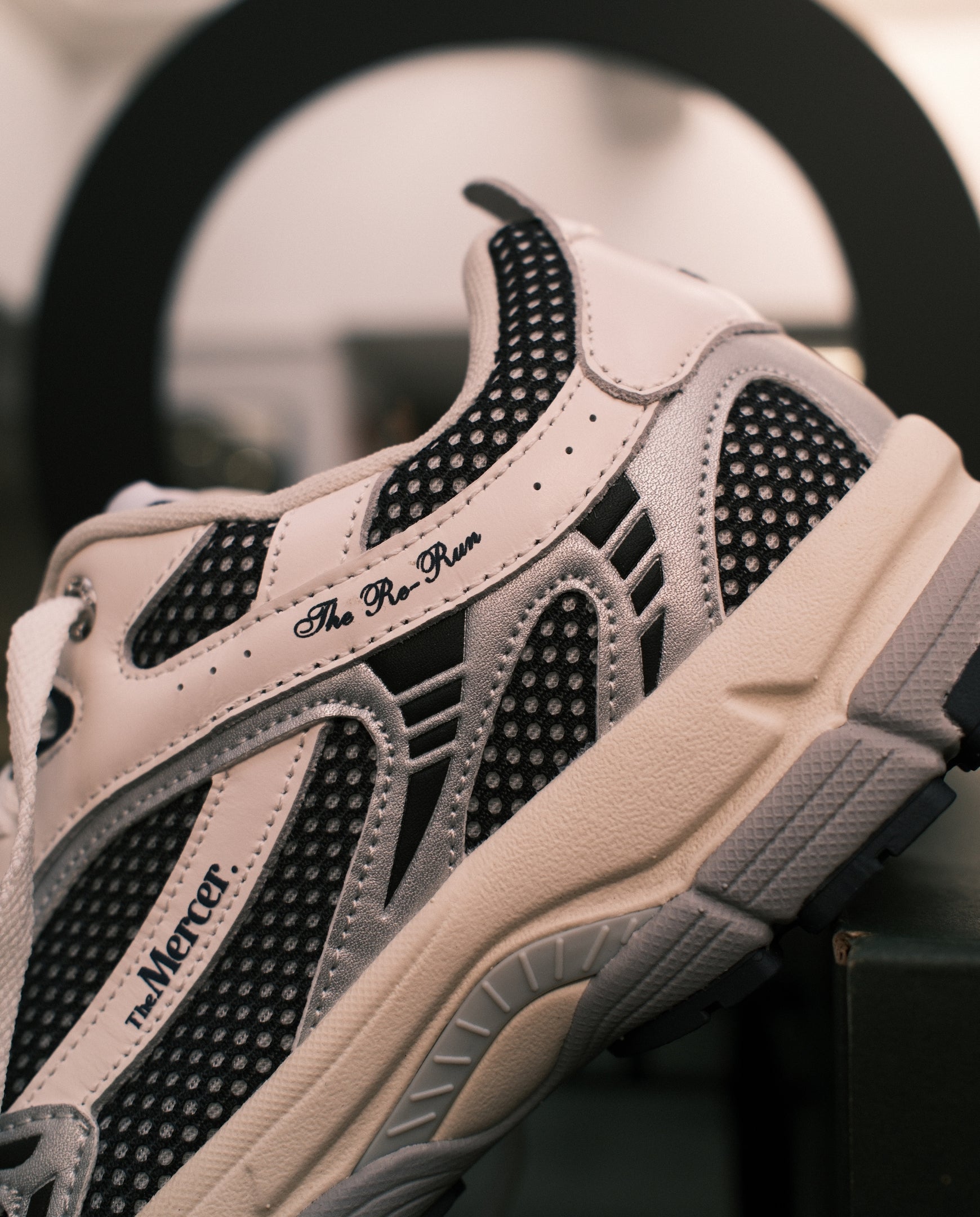 Lichtroze sneaker-detail met zwarte mesh en Mercer-logo