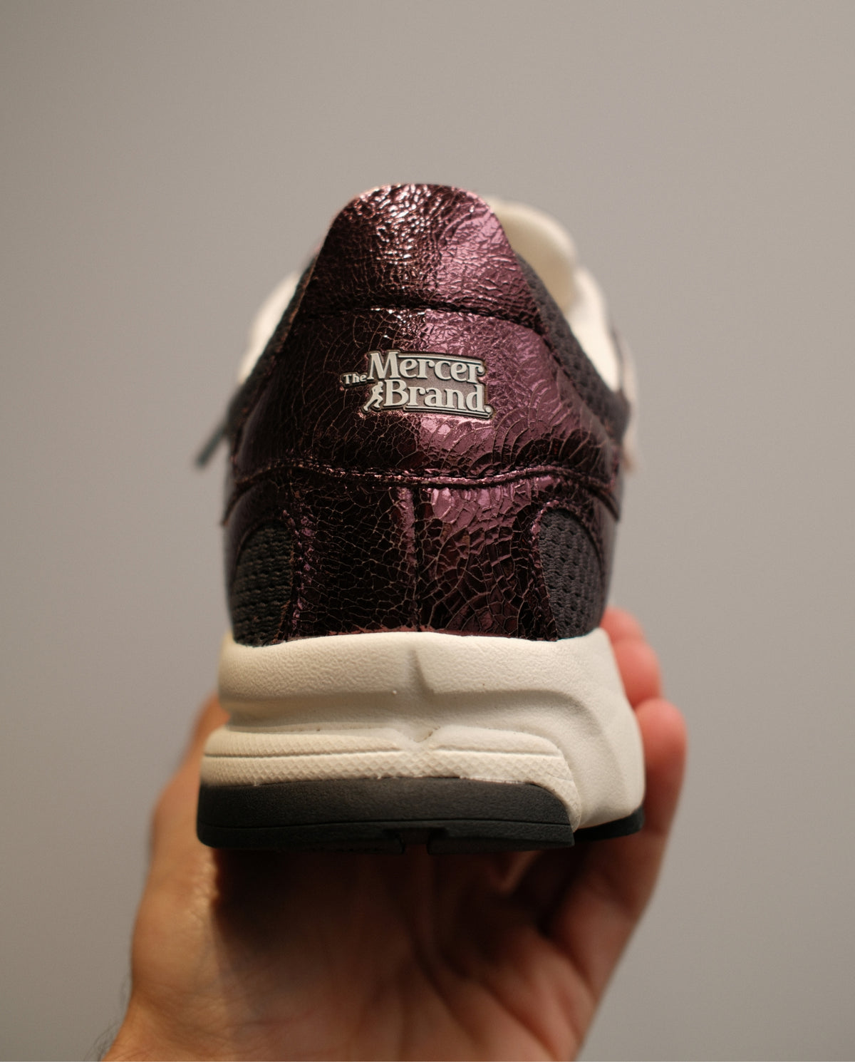 Donkerrode sneaker met witte hiel en Mercer Brand-logo op de achterkant