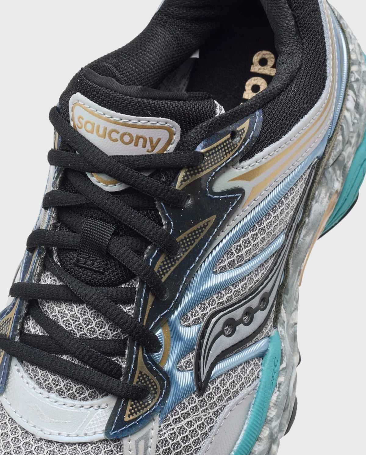 Saucony Progrid Omni 9 close-up: tong en veters met Saucony-label en blauwgrijze overlay